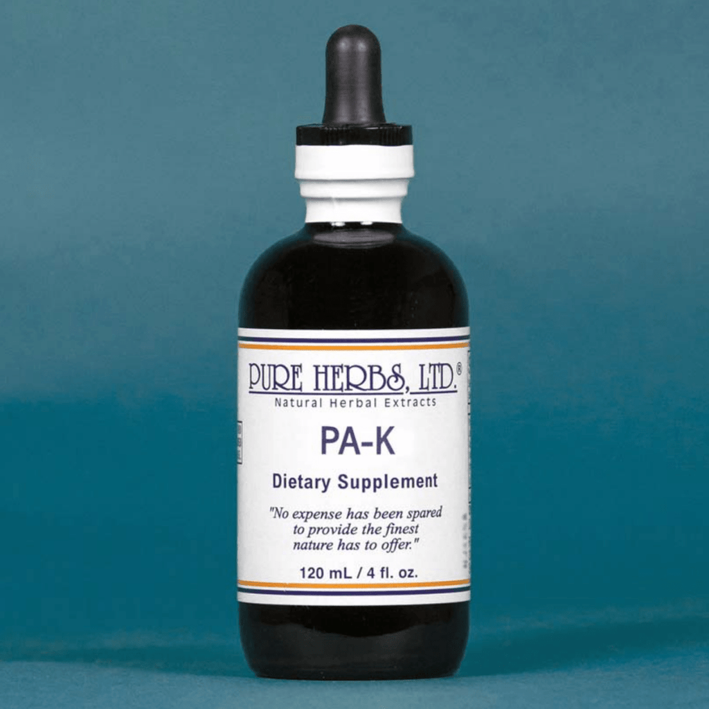 A dark amber glass dropper bottle of Pure Herbs Ltd. PA-K dietary supplement, featuring a white label with blue text, set against a solid slate blue background.